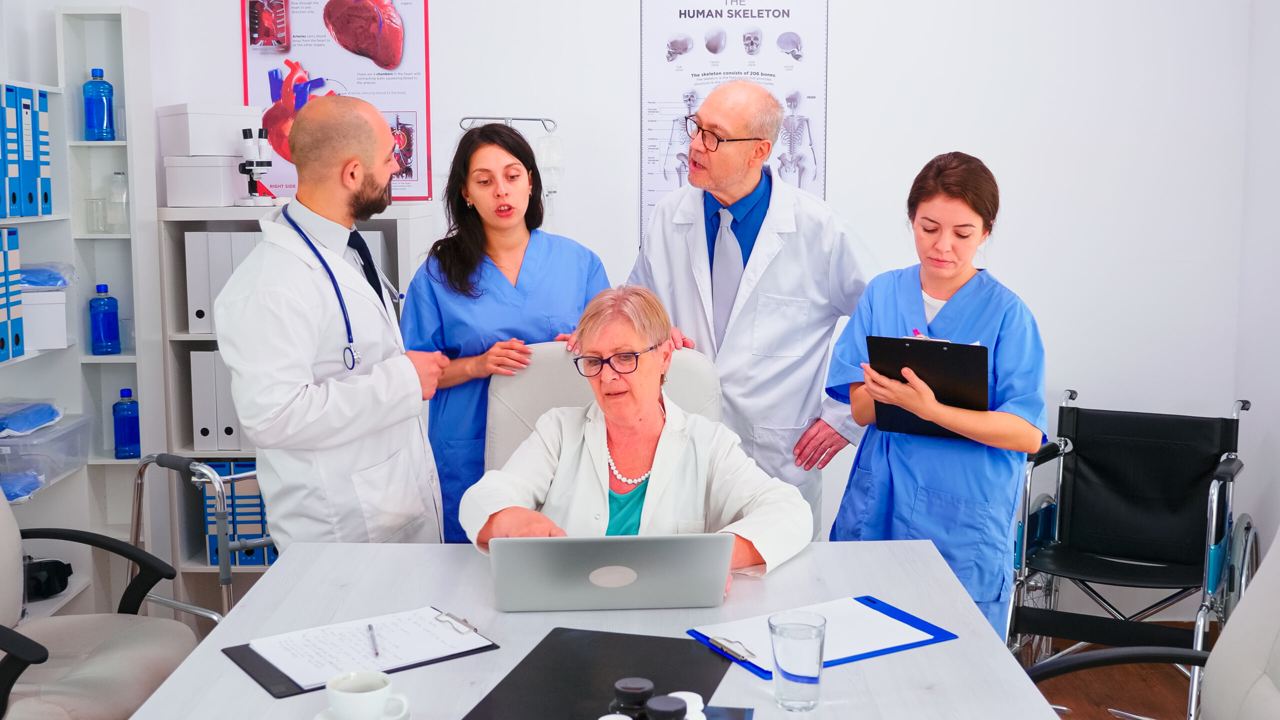mature-doctor-specialist-briefing-her-medical-team-conference-room-using-laptop-medical-team-teamwork-people-discussing-diagnosis-about-patients-treatment-issues-record-workplace